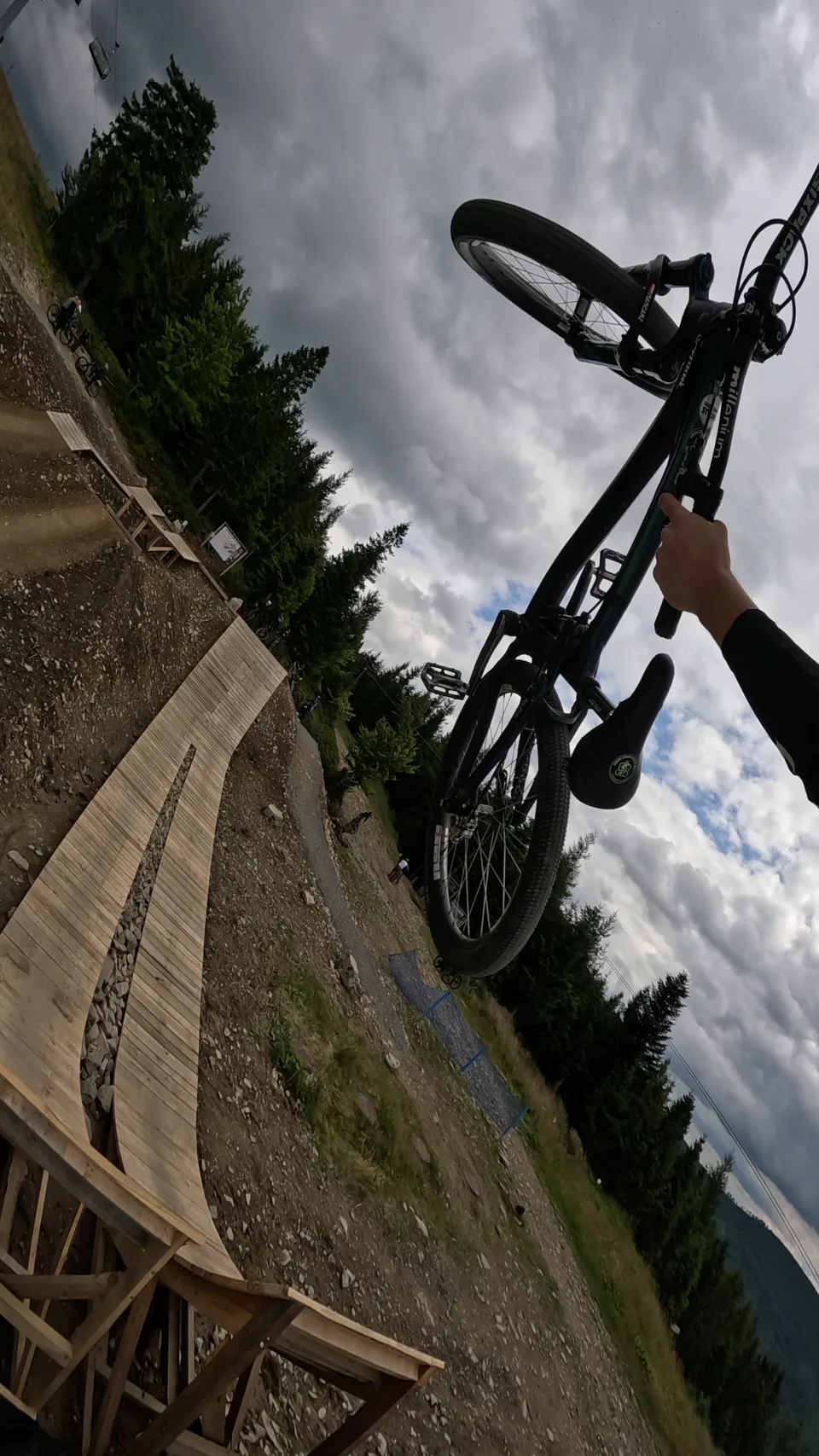 Mateusz Mamcarz performs a bike trick above a wooden feature